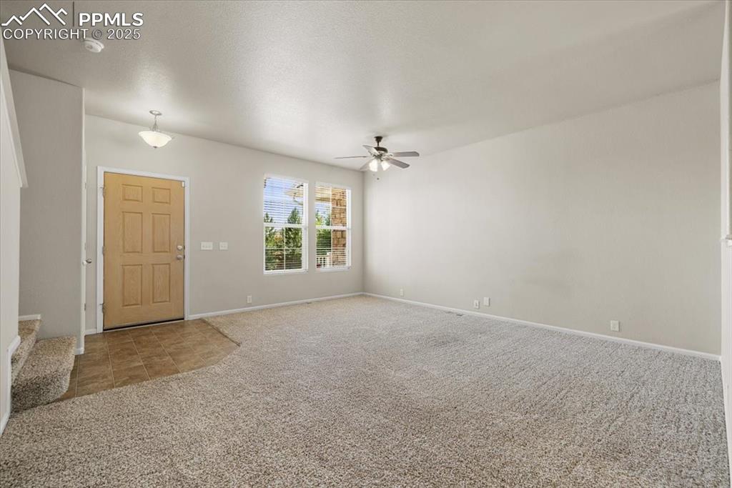 Image 8 of 42: Entrance foyer featuring stairway, light carpet, ceiling fan, a textured ce