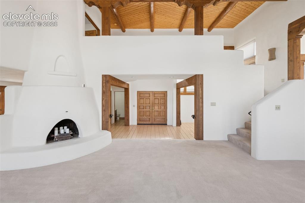 Image 12 of 46: A wood burning fireplace anchors the living room, while the double entry do