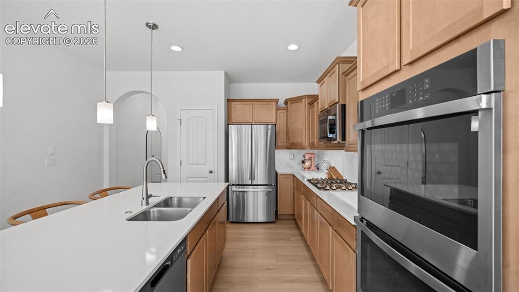 Image 10 of 38: Kitchen with light wood-finish cabinetry, stainless steel appliances, white