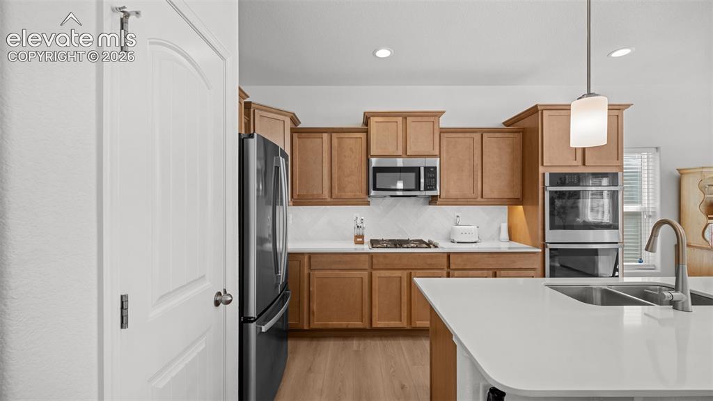 Image 11 of 38: Kitchen featuring a large island with an undermount sink, light wood-finish