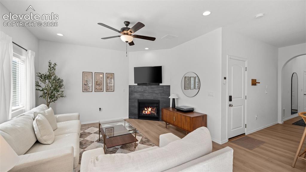 Image 13 of 38: Living area featuring a modern fireplace with dark stone surround, wood-fin