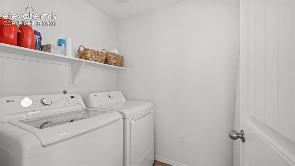 Image 16 of 38: Dedicated laundry space featuring white walls, open shelving, and a paneled