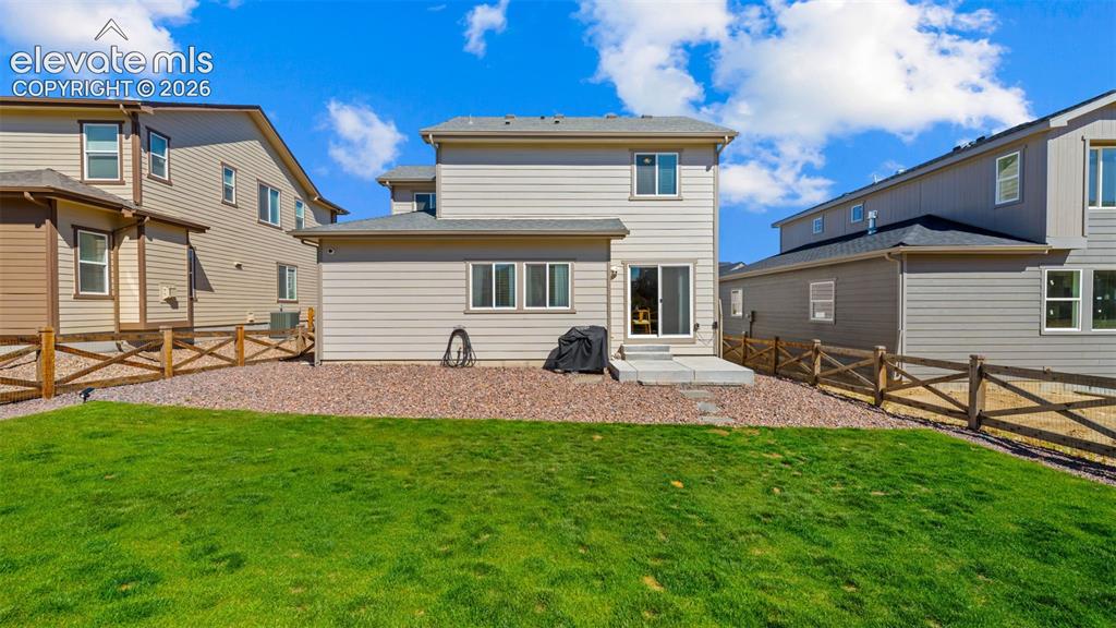 Image 25 of 38: Expansive grassy yard with a gravel border, featuring a split-rail fence