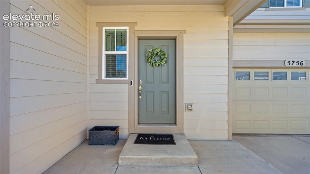 Image 4 of 38: Front entry featuring a light gray door with gold-tone hardware, an adjacen