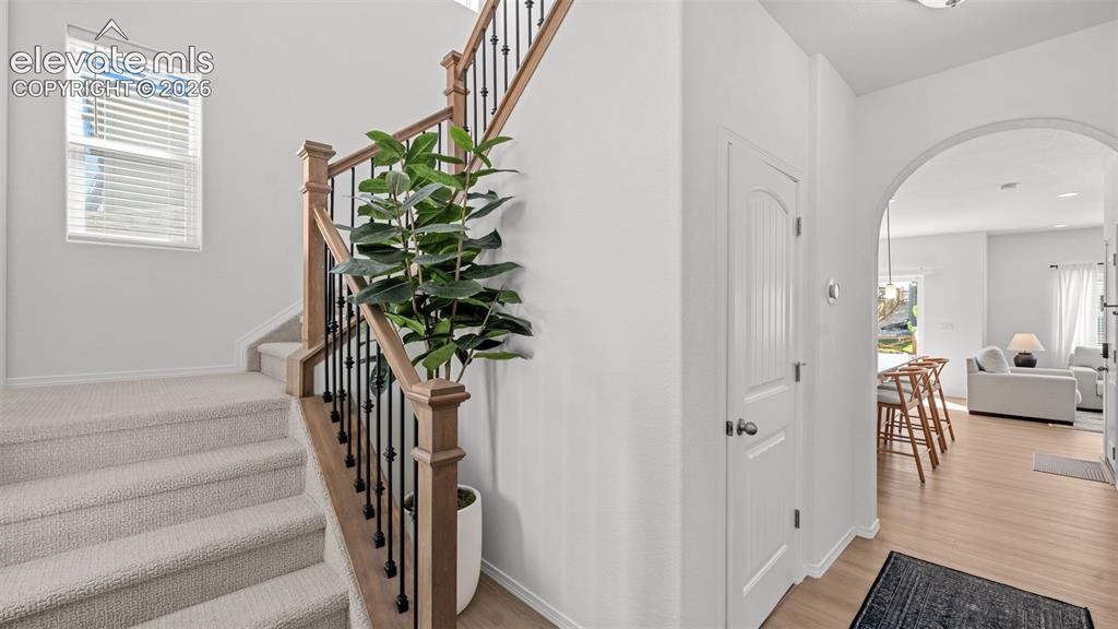 Image 5 of 38: Carpeted staircase with wood-finish handrail and black metal balusters