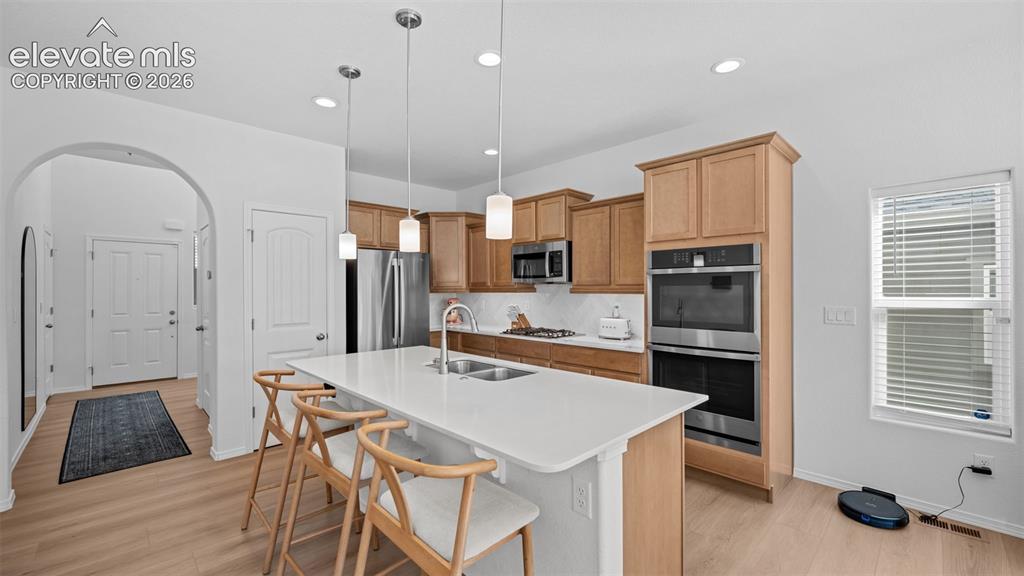 Image 7 of 38: Modern kitchen featuring a large island with seating, stainless steel appli