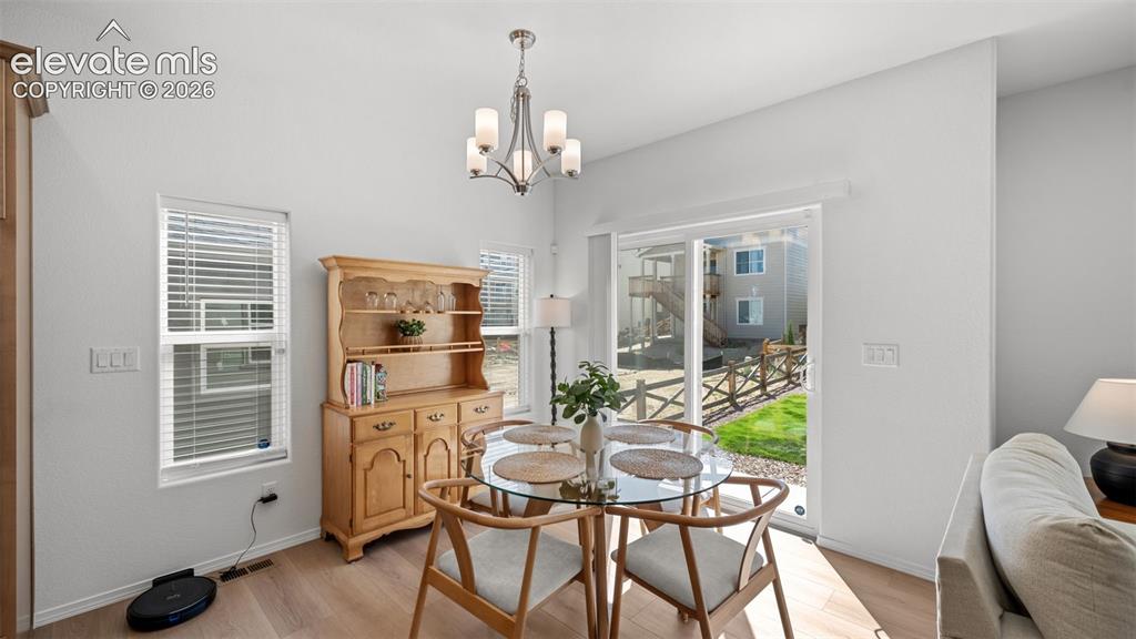 Image 8 of 38: Dining area featuring a contemporary chandelier, multiple windows with blin