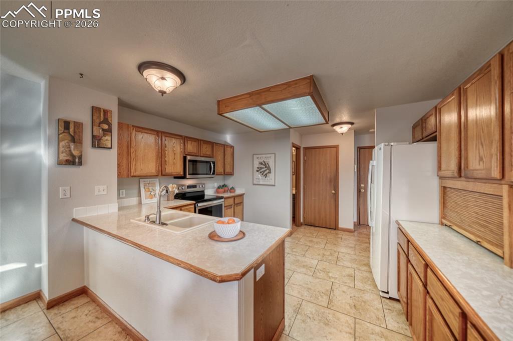 Image 12 of 46: Kitchen featuring light countertops, stainless steel appliances, wood finis