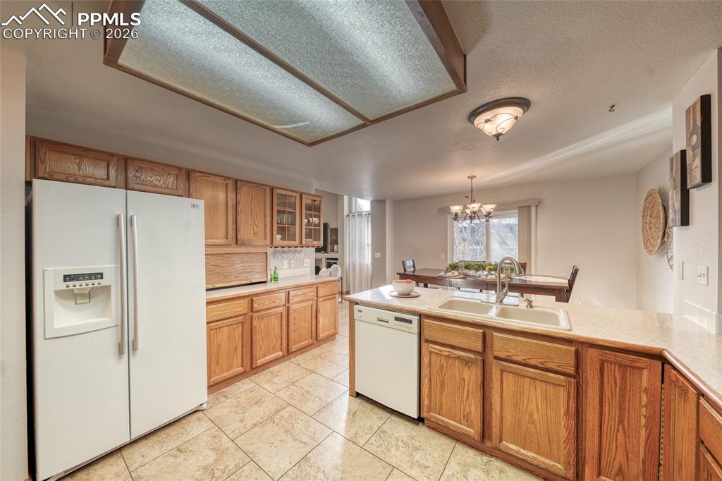Image 16 of 46: Kitchen with white appliances, wood finish cabinetry, glass fronted cabinet