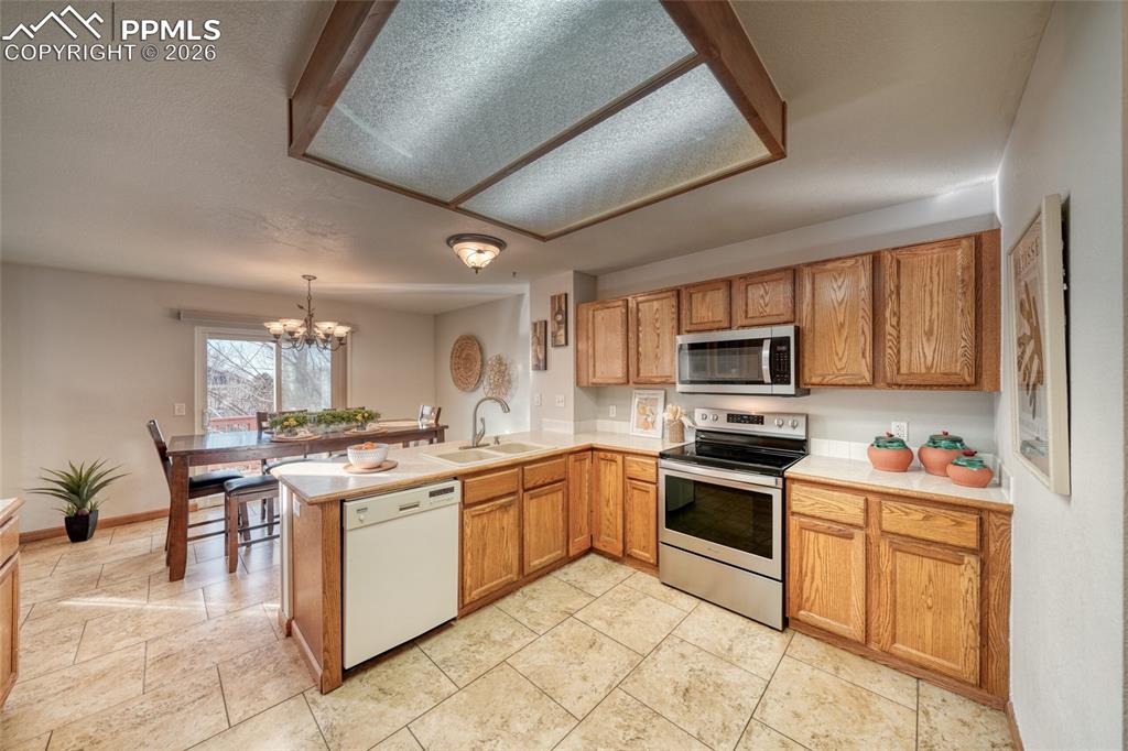 Image 17 of 46: Kitchen featuring stainless steel appliances, light countertops, a peninsul