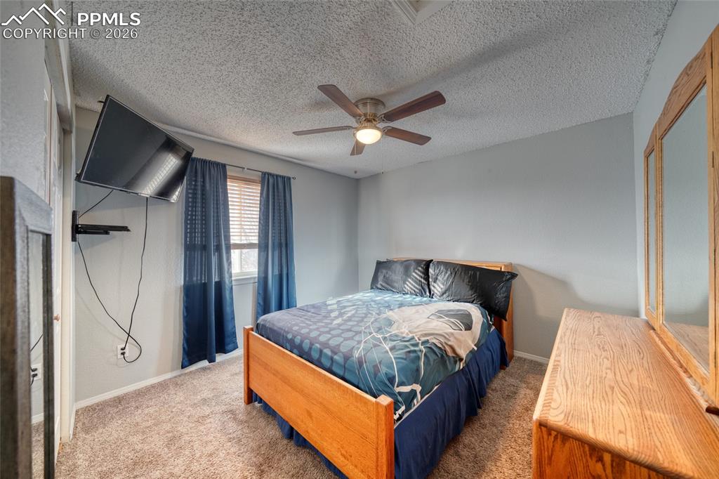 Image 22 of 46: Bedroom with carpet floors, ceiling fan, and a textured ceiling