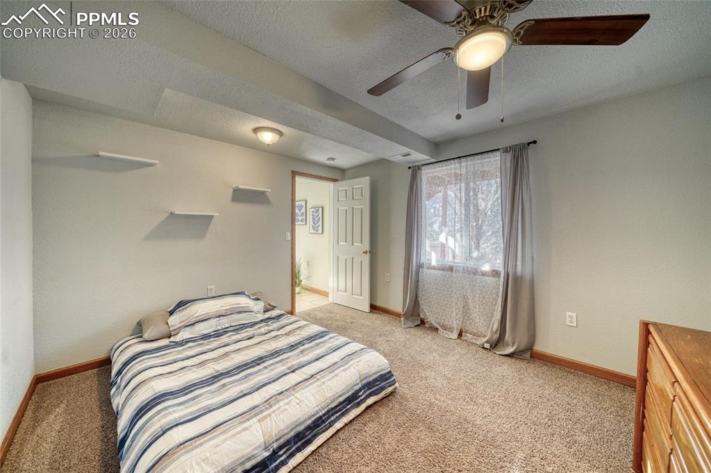 Image 31 of 46: Bedroom featuring a textured ceiling, light colored carpet, and ceiling fan