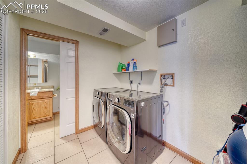 Image 32 of 46: Laundry room featuring separate washer and dryer, a textured ceiling, a tex