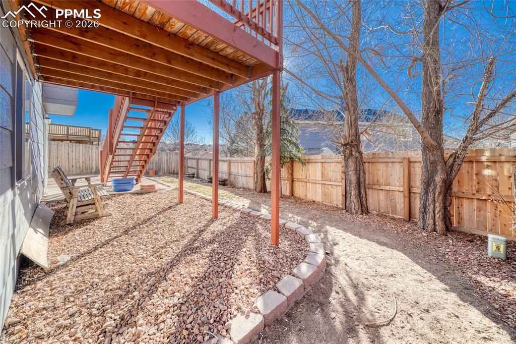 Image 36 of 46: Fenced backyard with a wooden deck and a patio area