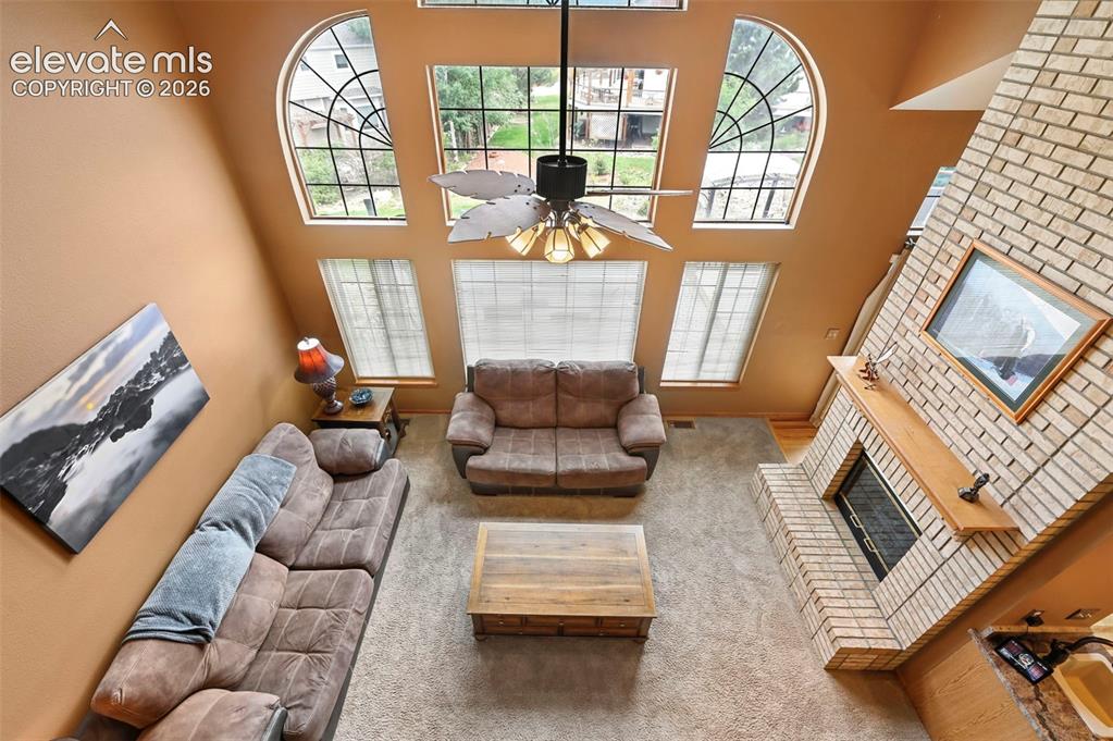 Image 10 of 50: Two-story living area with arched windows, brick-surround fireplace, wood m