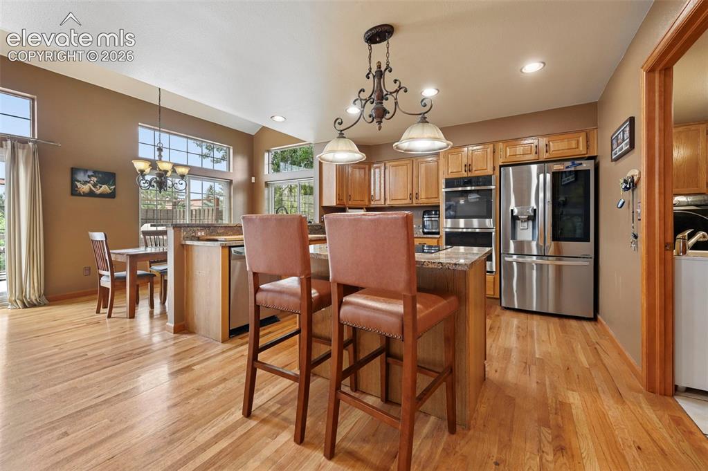 Image 11 of 50: Kitchen featuring wood-finish flooring, a central island with countertop se