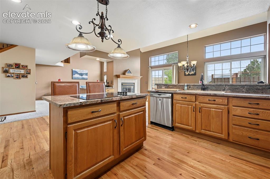 Image 12 of 50: Kitchen featuring wood-finish flooring, an island with a built-in cooktop,