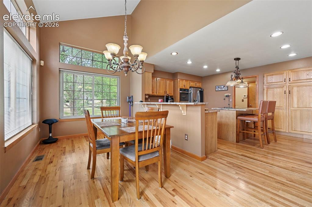 Image 14 of 50: Vaulted ceiling with a decorative chandelier, expansive windows, wood-finis