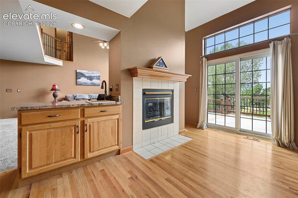 Image 16 of 50: Transition between kitchen and family room with a sink and fireplace.