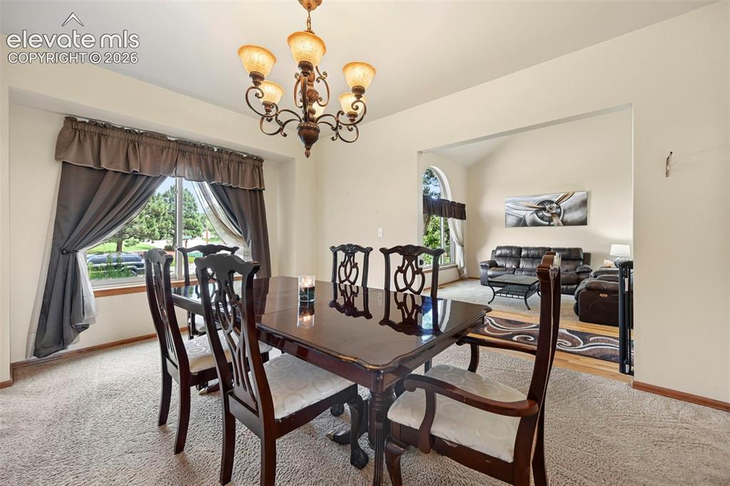 Image 17 of 50: Tray ceiling with an ornate chandelier, carpeted flooring, and a large wind