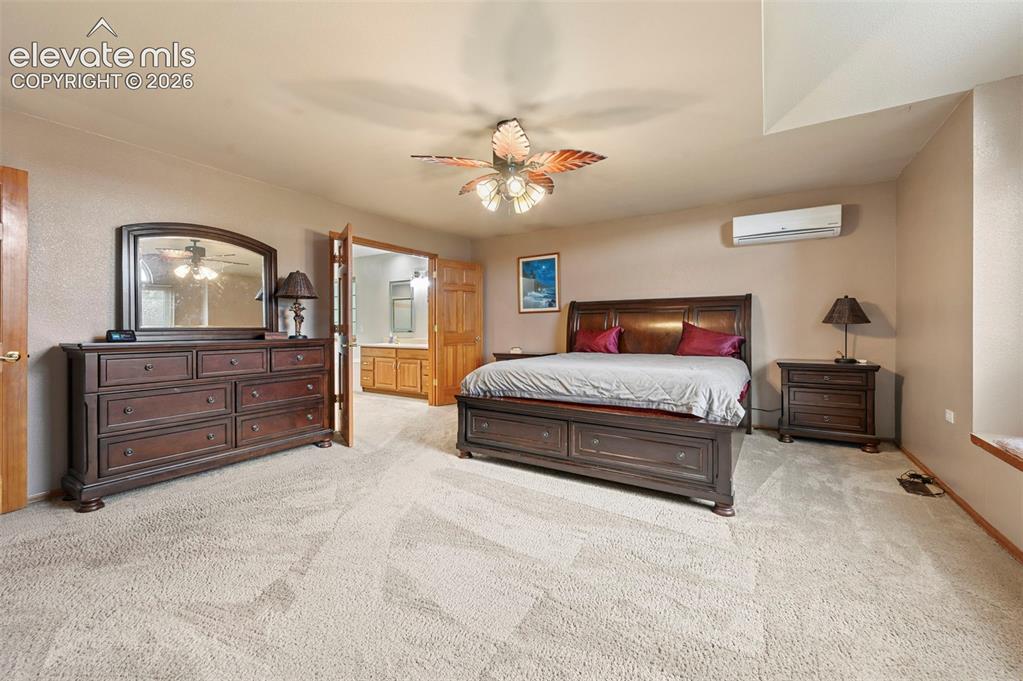 Image 18 of 50: Primary bedroom with ceiling fan, arched window, window bench, wall-mounted