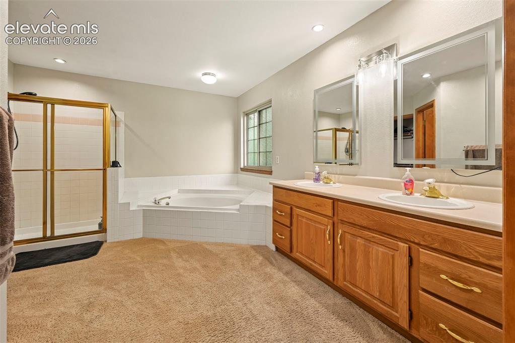 Image 21 of 50: Dual vanity with wood-finish cabinetry, built-in soaking tub, separate show