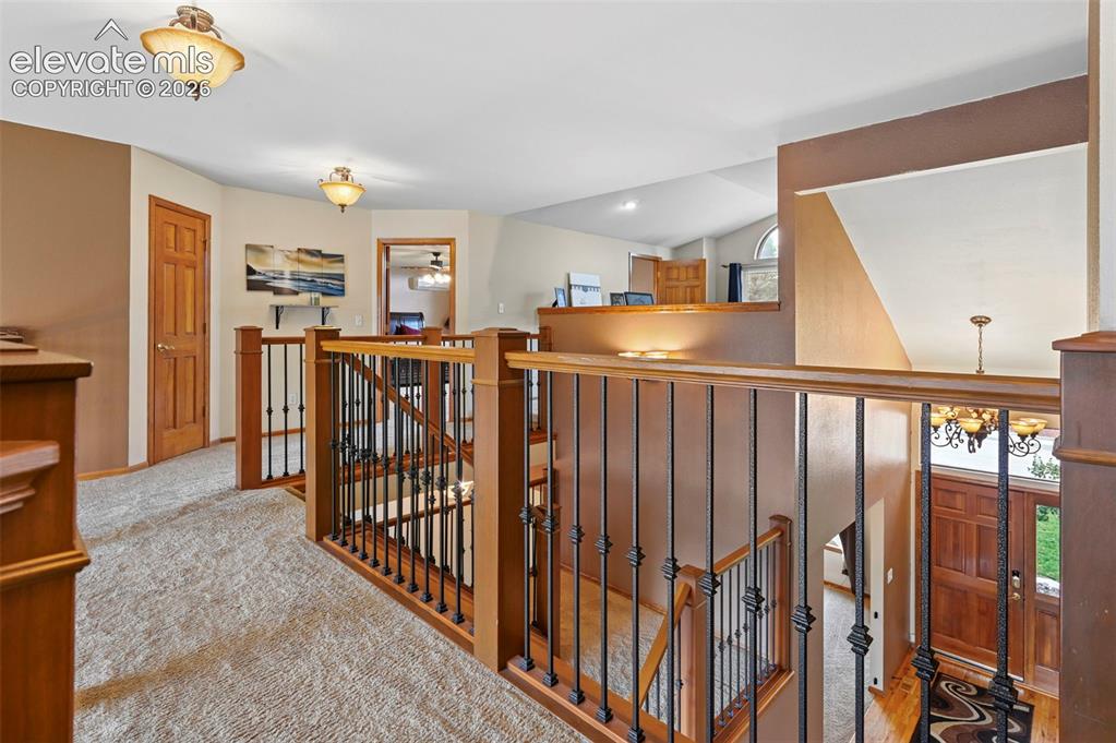 Image 25 of 50: Upper level landing featuring wood-finished doors, carpeted flooring, and d