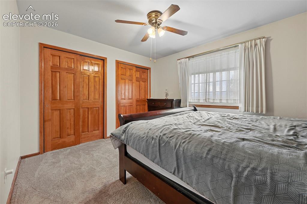 Image 26 of 50: Second floor bedroom, warm-toned wood paneled closet doors, neutral wall pa