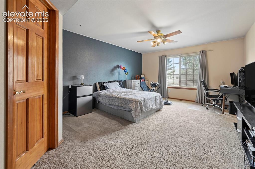Image 28 of 50: Main level bedroom with light-colored wall-to-wall carpeting, wood-paneled
