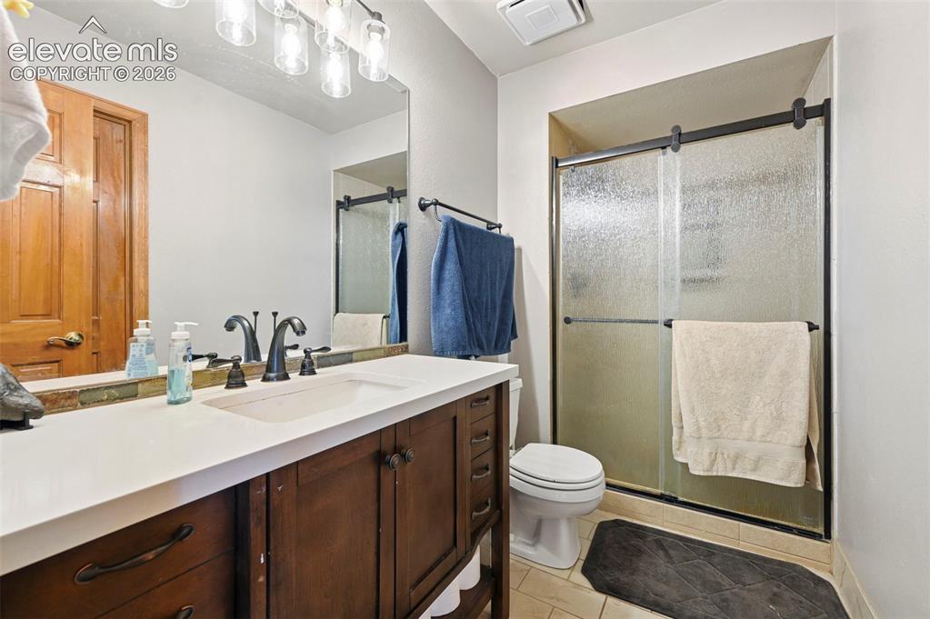 Image 29 of 50: Main level bathroom with wood-finish vanity and white countertop, undermoun