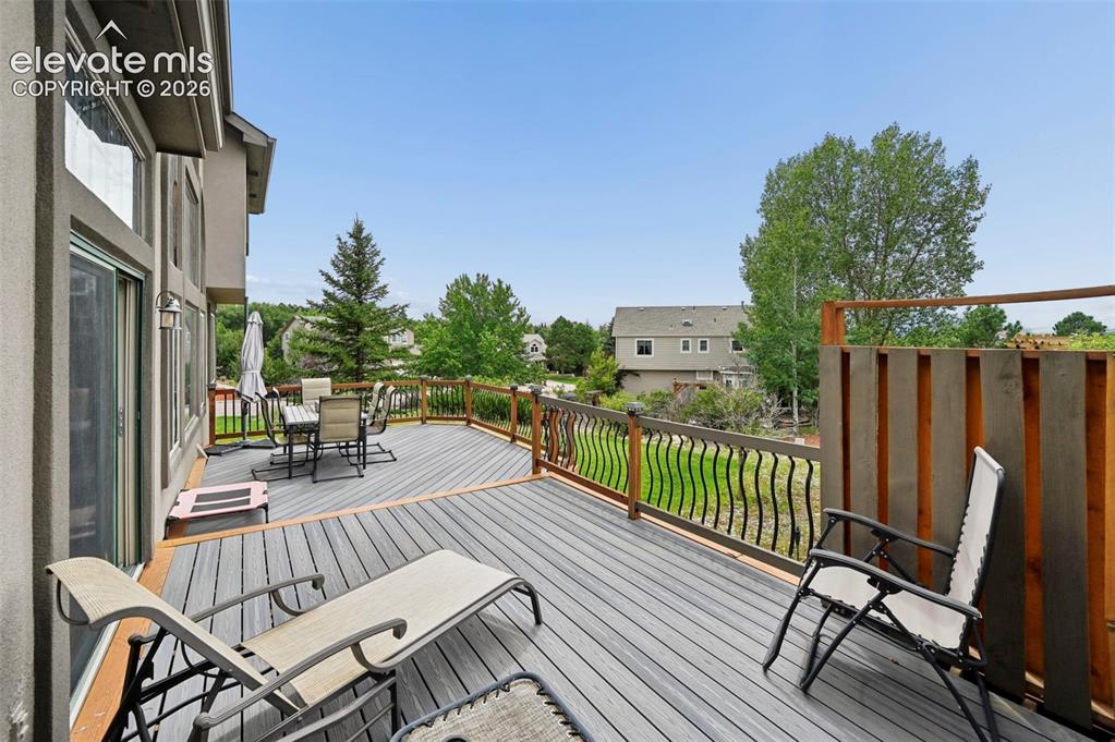 Image 36 of 50: Expansive elevated deck with composite decking, wrought iron railing, and a