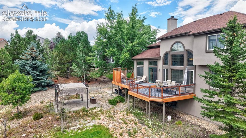 Image 42 of 50: Multi-level backyard and wood-deck with dark railings, expansive arched win