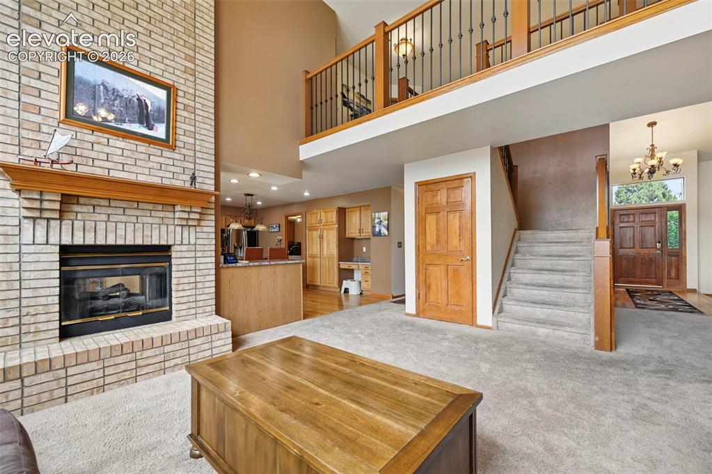 Image 7 of 50: Brick fireplace with wood mantel, two-story ceiling, open mezzanine with wr