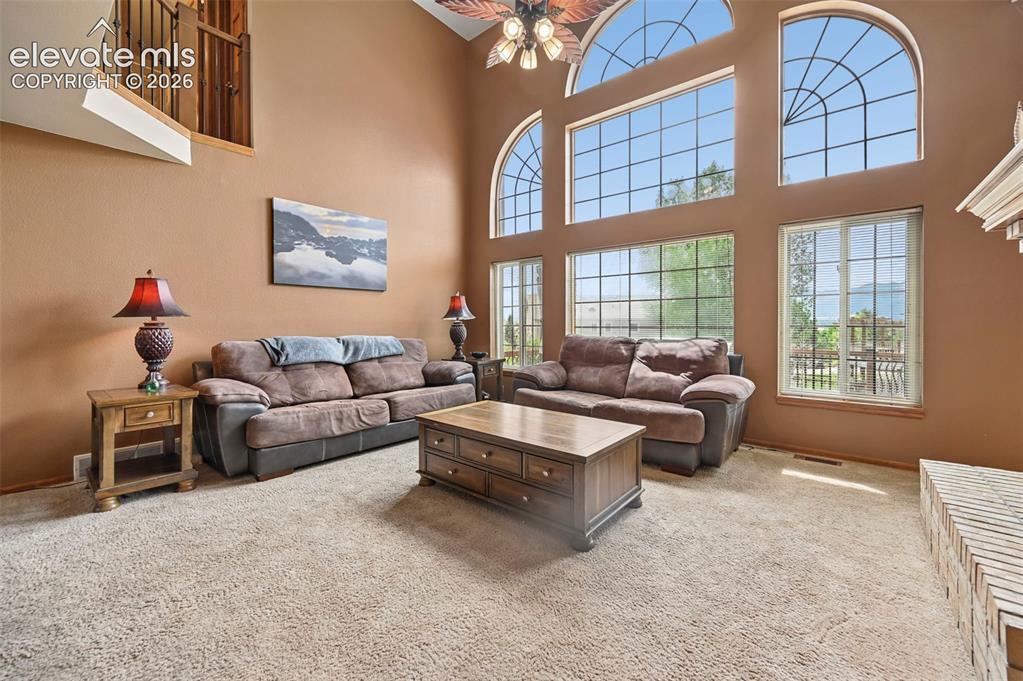 Image 8 of 50: Two-story family room with high ceilings, arched transom windows, and an up