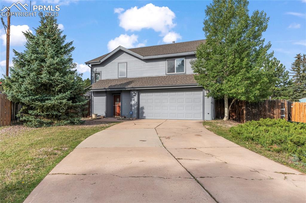 Caption: Traditional-style house featuring a garage, roof with shingles, and concrete driveway