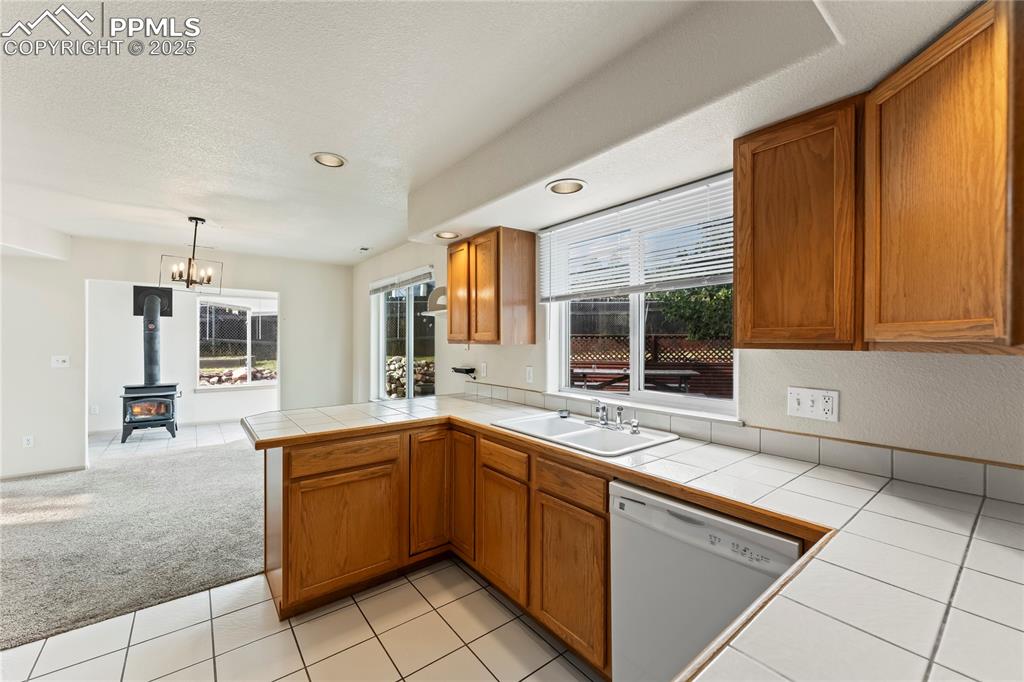 Image 10 of 38: Kitchen with tile countertops, light carpet, light tile patterned flooring,