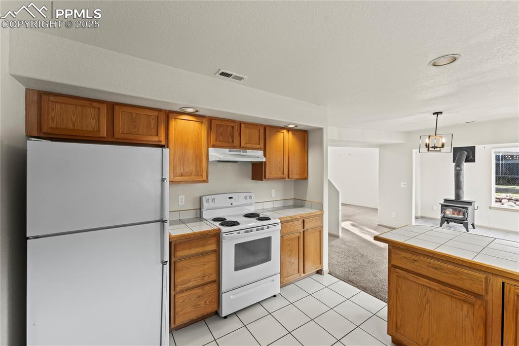 Image 11 of 38: Kitchen featuring tile counters, white appliances, light tile patterned flo