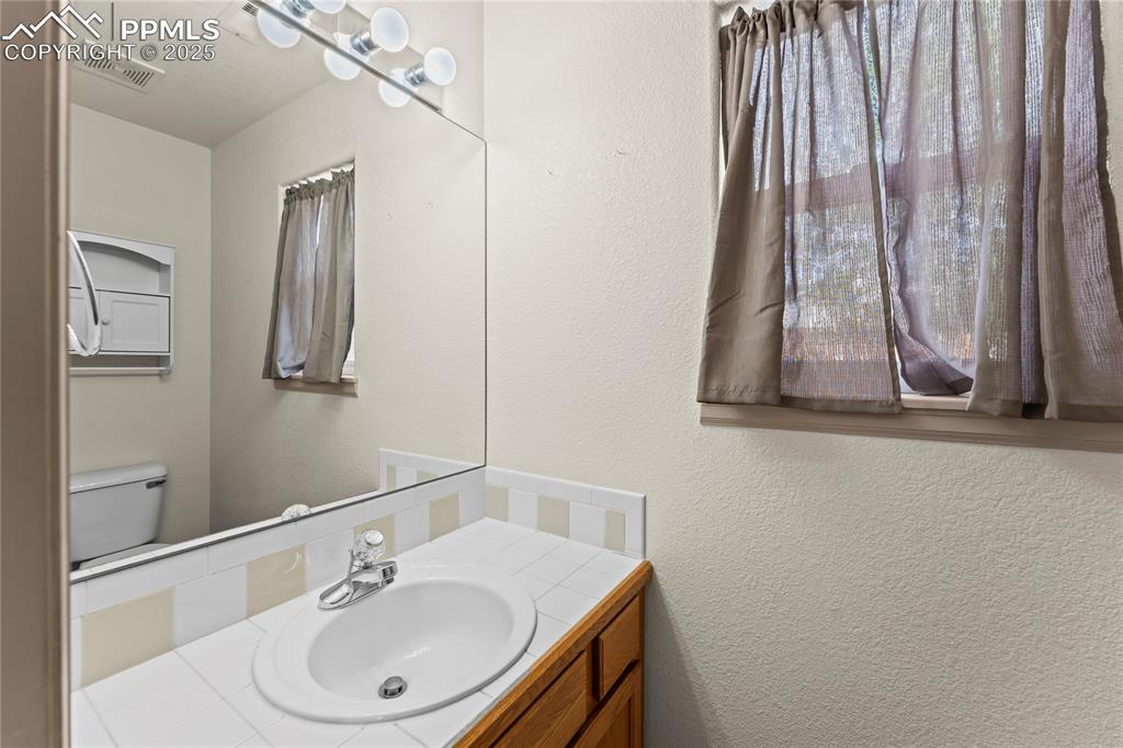 Image 14 of 38: First floor powder room featuring a textured wall and vanity