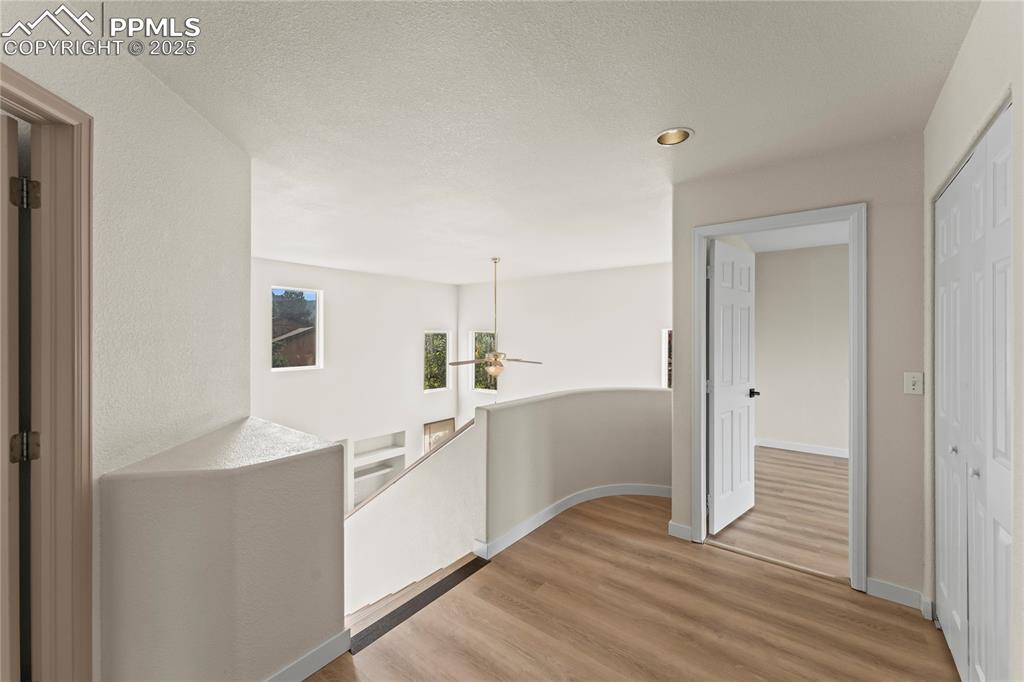 Image 15 of 38: Hall featuring an upstairs landing, wood finished floors, and a textured ce