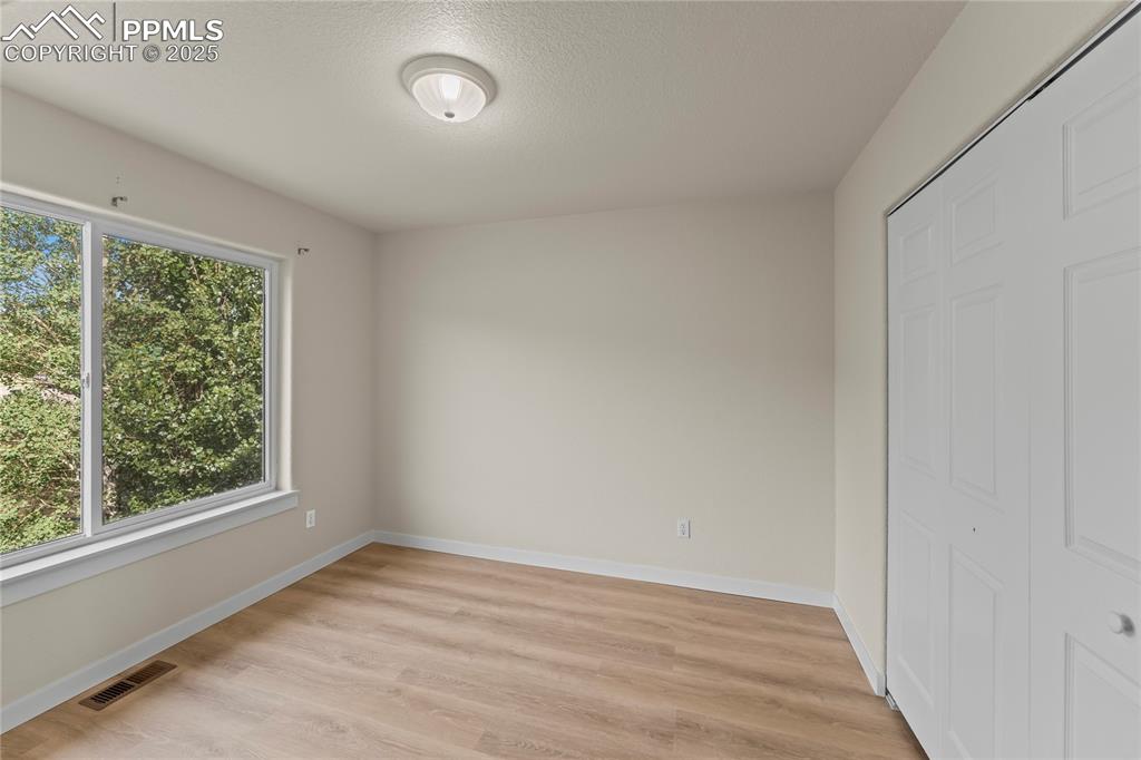Image 20 of 38: Unfurnished bedroom featuring light wood-style floors, a textured ceiling, 