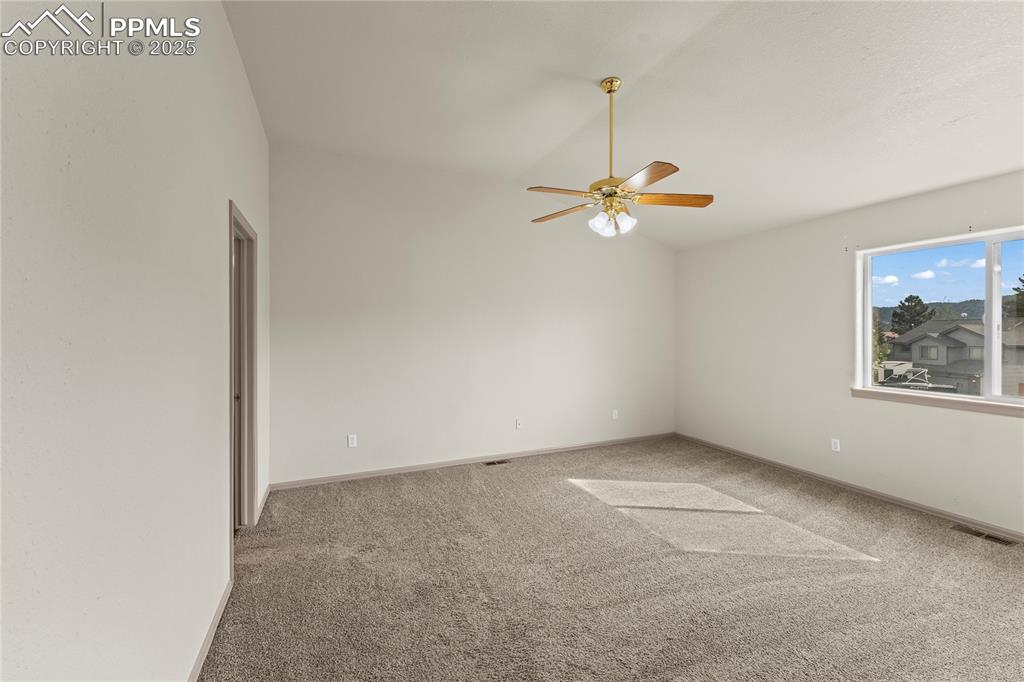 Image 22 of 38: Carpeted spare room with vaulted ceiling and ceiling fan