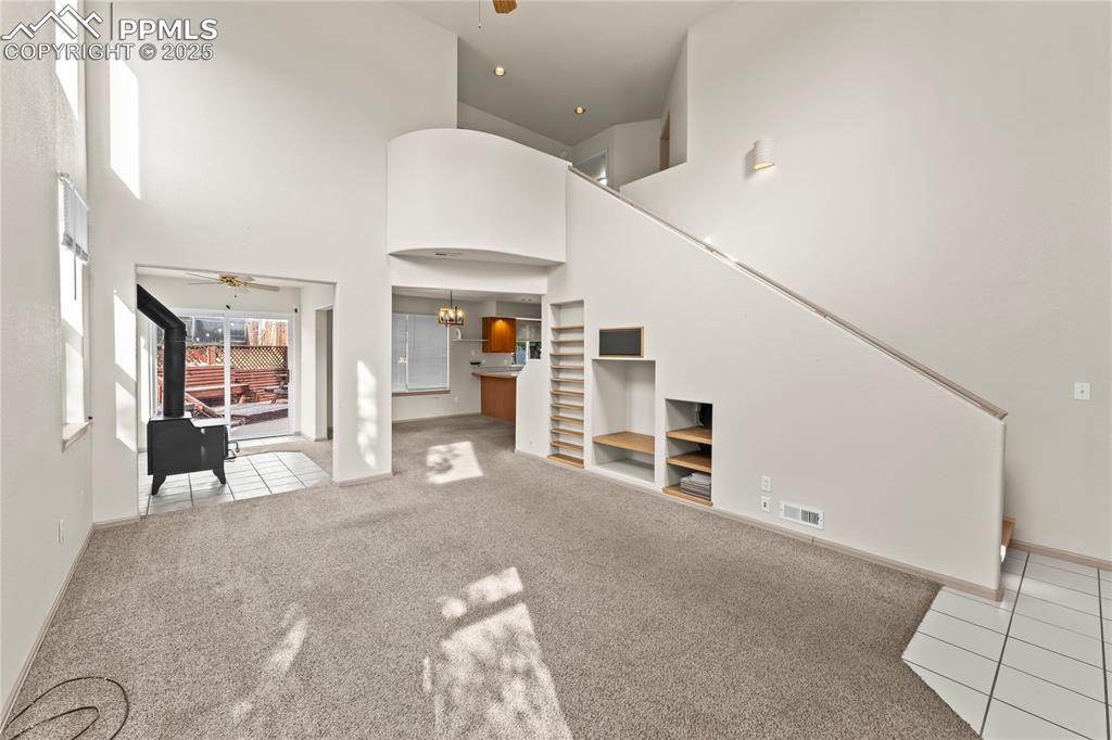 Image 6 of 38: Tiled living area featuring a ceiling fan, a towering ceiling, carpet floor