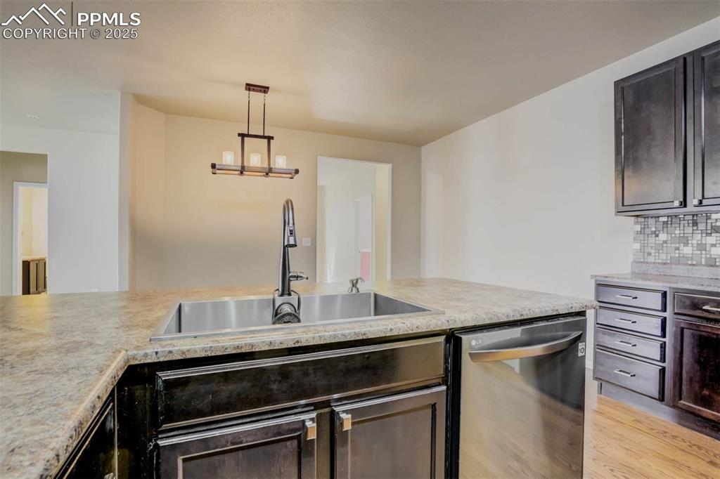 Image 10 of 47: Kitchen featuring a sink, dark brown cabinets, light countertops, and dishw