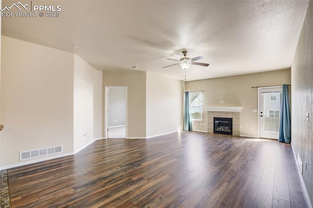 Image 13 of 47: Unfurnished living room featuring a ceiling fan, visible vents, a tile fire
