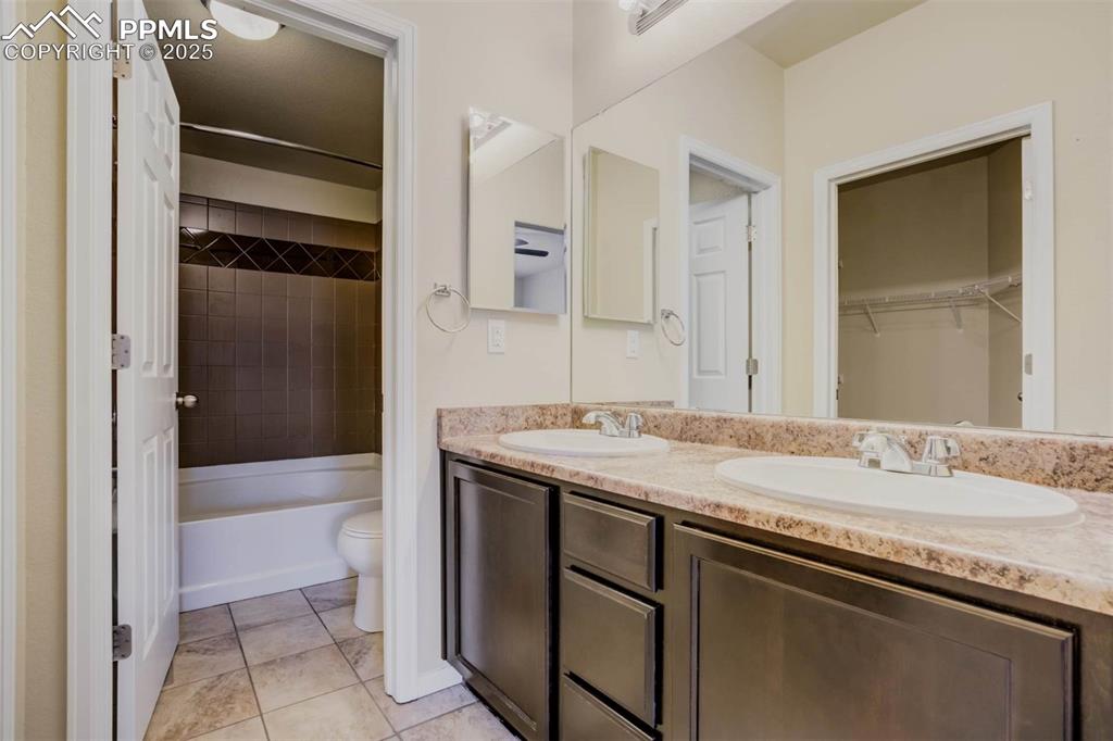 Image 19 of 47: Bathroom with a sink, tile patterned floors, toilet, and double vanity