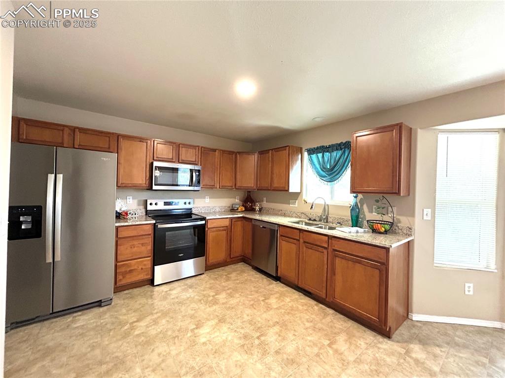 Image 10 of 43: Kitchen with a sink, appliances with stainless steel finishes, brown cabine