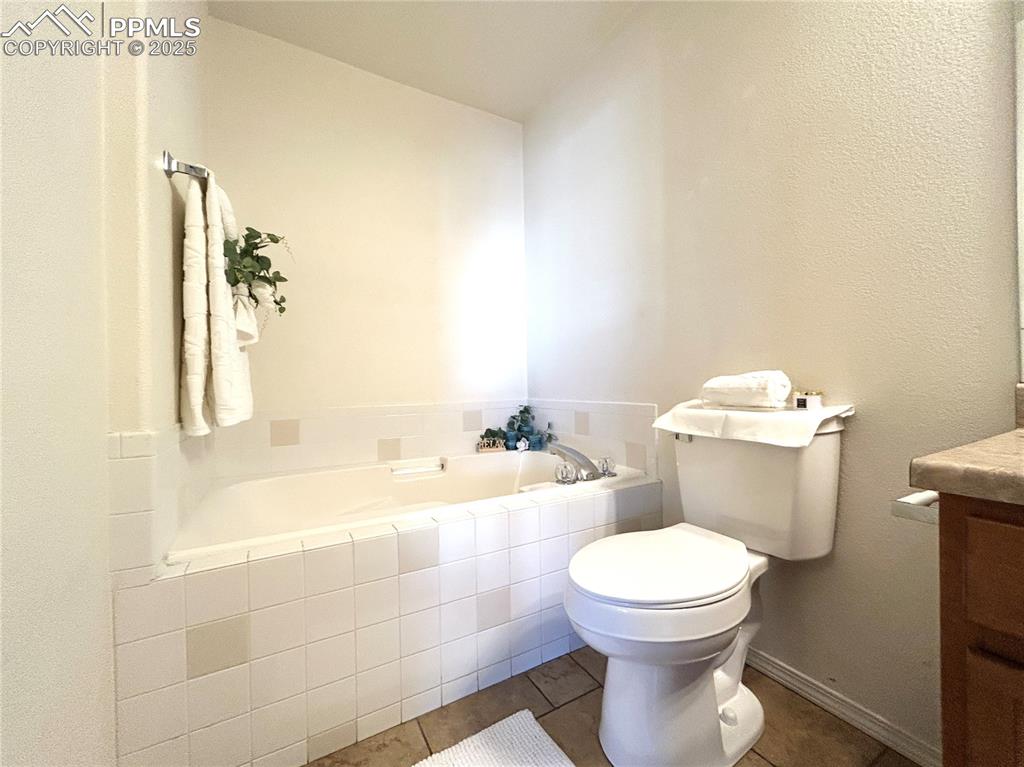 Image 17 of 43: Bathroom featuring toilet, tile patterned floors, a garden tub, and vanity