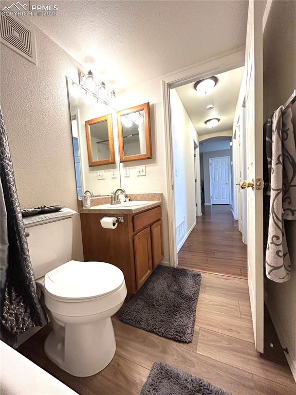 Image 20 of 43: Bathroom with a textured wall, vanity, a textured ceiling, wood finished fl