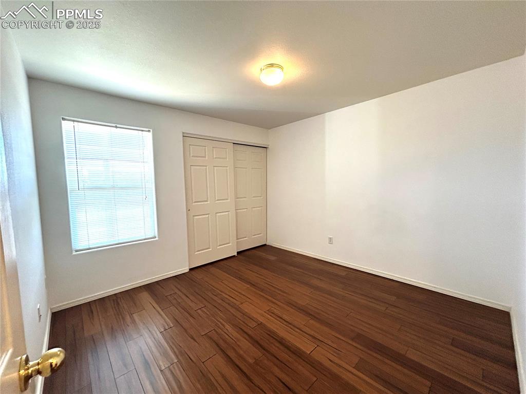 Image 22 of 43: Secondary Bedroom features a closet and dark wood-style floors