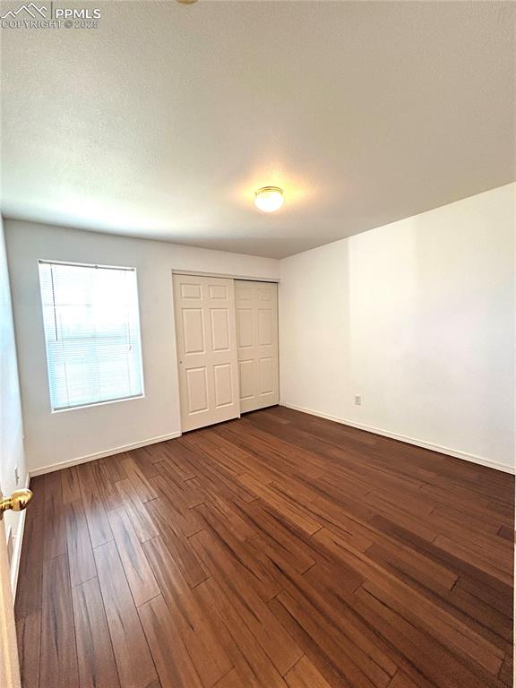 Image 24 of 43:  secondary bedroom featuring baseboards, a closet, and dark wood-type floor